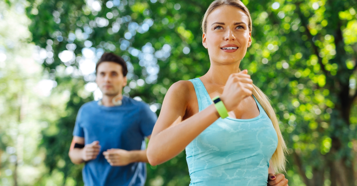 Two people jogging outdoors wearing fitness trackers to support metabolic health habits